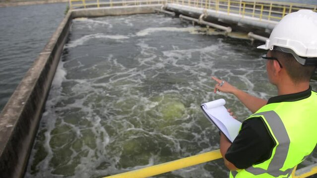 an engineer stand aside at the waste water pool and check the air tube under the water to make sure that every system work properly and the gauge at standard value, waste water treatment