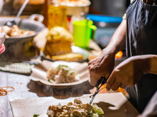 Indonesian street vendor preparing tahu tek. Tahu tek is one of the typical dishes of the city of Lamongan. consists of half-cooked fried tofu and lontong cut into small pieces with scissors.
