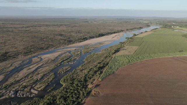 Drone and aerial footage reveal contrasting sugarcane and pepper farms, divided by a seasonal river, bordering Kruger National Park. South Africa.