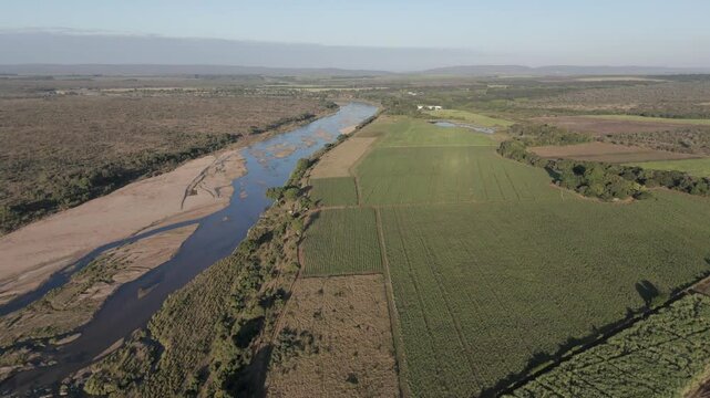 Drone footage reveals contrasting sugarcane and pepper farms, divided by a seasonal river, bordering Kruger National Park. South Africa.