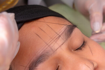 Using pre-inked mapping string to make guide lines around the eyebrows for approximate shaping for...