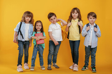 Obraz premium Standing and posing. Kids are together against yellow background
