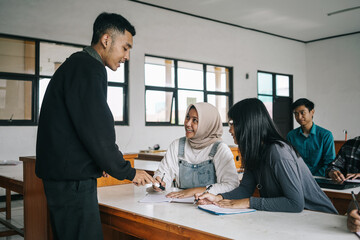 Teenager Students Listening To Young Male Teacher Explaining In Front Of The Class