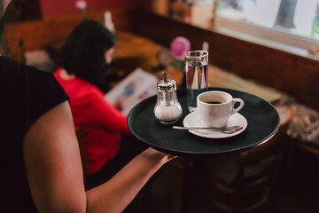 Bedienung serviert Kaffee auf Tablett