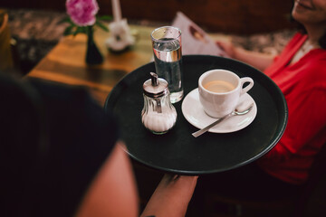 Bedienung serviert Kaffee auf Tablett