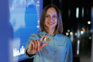 Close up of digital currency coin in hand. Businesswoman is against projector with graphs, indoors