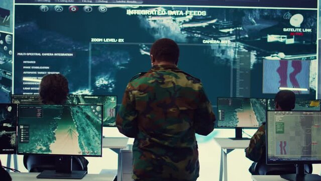 Female brigadier general conducing anti terrorism mission in military operations room, employing radar systems to detect and track enemy aircraft or missiles. Secret service program. Camera B.