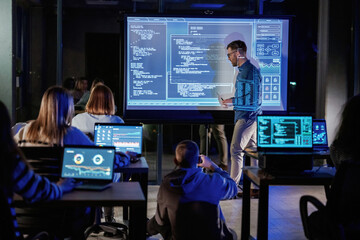 Talking about project. Male business trainer is against projector with data, teaching people