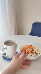 a bowl of oat meal and cup of coffee with milk on the white table in the morning