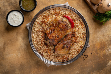 Delicious colorful Afghan rice pilaf Kabuli pulao with lamb or Chicken and raisin, carrot, nut, spices closeup on the plate on the wooden table.