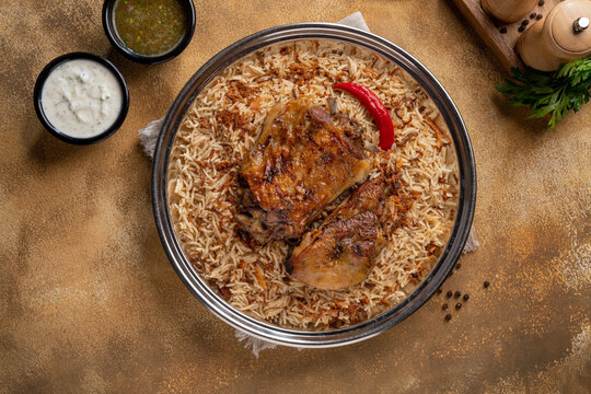 Delicious colorful Afghan rice pilaf Kabuli pulao with lamb or Chicken and raisin, carrot, nut, spices closeup on the plate on the wooden table.