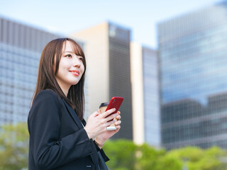 Fototapeta premium 街でスマホを使う女性ビジネスパーソン