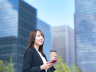 街角でスマホを使う女性ビジネスパーソン