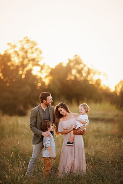 Family of four enjoying a golden sunset in a grassy field, inter