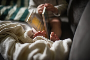 Child reading a board book with feet wrapped in a cozy blanket