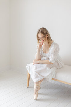 Ballernia gracefully sits on linen bench in white studio