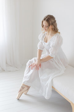 Ballernia gracefully sits on linen bench in white studio