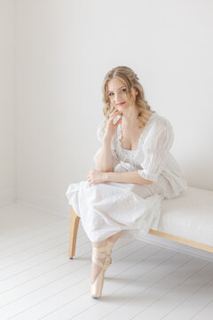 Ballernia gracefully sits on linen bench in white studio