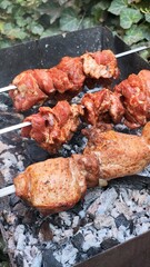 Three pieces of meat are being cooked on a grill. The meat is marinated and has a spicy flavor