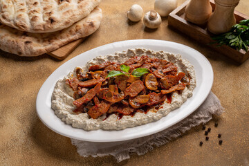 sliced chicken steak with mushroom and mutabal in a plate.
