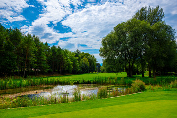 Golf Course with a Lake and Clouds in a Sunny Summer Day in Granges, Valais, Switzerland.