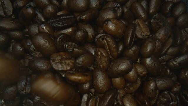 Close up of pile of aromatic blended roasted coffee bean scattering at table with roasted coffee bean falling surrounded with separated blurring black background. Top down view. Slow motion. Pabulum.