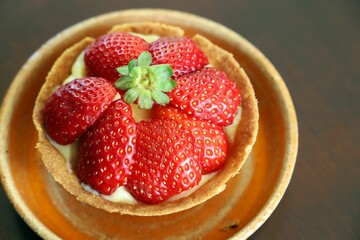 Close-up of a delicious strawberry tart with fresh strawberries on top in a ceramic plate
