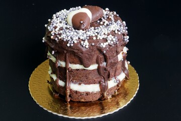 Decadent chocolate cake with layers of cream, topped with chocolate ganache and sprinkles