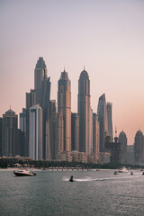 Fototapeta premium Dubai city skyline at sunset from the sea and jet skis