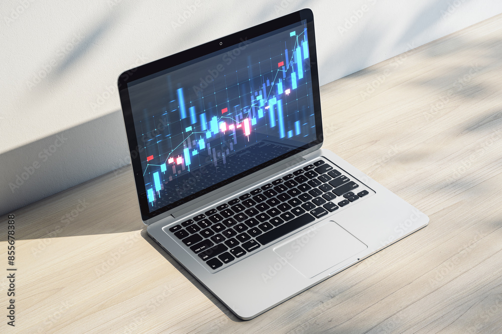 Poster close up of laptop on office desk with shadows and glowing blue candlestick forex chart on screen. f