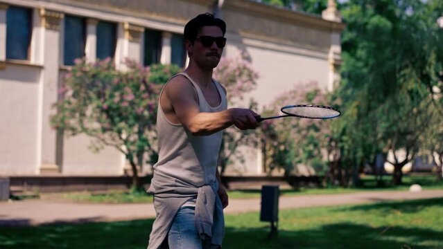 outdoors in a park with trees young handsome brunette guy in jeans and a white T-shirt, a brunette stuffing a shuttlecock warming up before playing bambinton