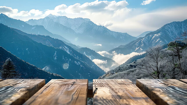 A wooden platform overlooking a breathtaking mountain range with snow-capped peaks and a valley filled with clouds.