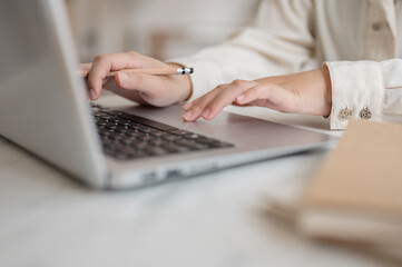 A close-up image of a businesswoman working on her laptop computer, typing on the laptop keyboard.