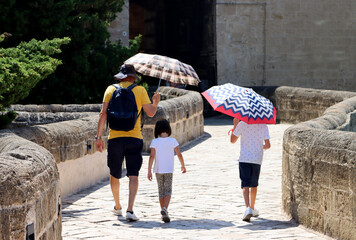 Father protects his children with umbrellas from the sun on a very hot day. Heat record with...