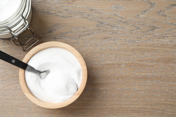 Baking soda in bowl on wooden table, top view. Space for text