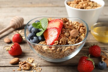 Tasty granola with berries, nuts and mint on wooden table