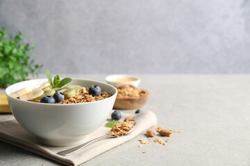 Tasty granola with fresh fruits on grey table, space for text