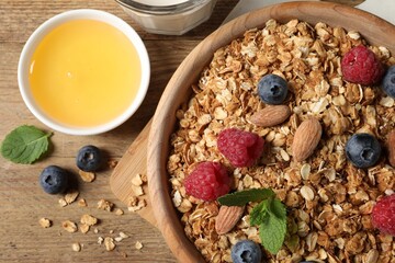 Tasty granola with berries, nuts and mint on wooden table, flat lay