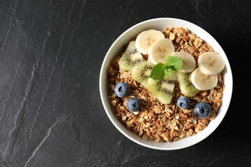 Tasty granola with fresh fruits on black table, top view. Space for text