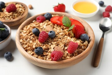 Tasty granola with berries, nuts and mint on white table