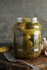 Pickled cucumbers in jar and garlic on table