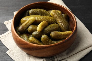 Pickled cucumbers in bowl on grey wooden table, closeup