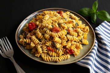 Homemade Baked Boursin Pasta on a Plate on a black background, side view.
