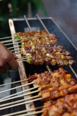 hand holding skewer to be cooked