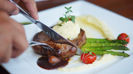 hand slicing sirloin steak with spoon