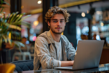 Young Man Working on Laptop in Cozy Cafe 