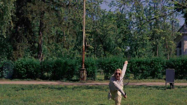 outdoors in a park with trees a young brunette guy with a blonde girl playing bambinton best friends relaxing together the girl serves