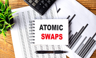 ATOMIC SWAPS text on notebook on chart with calculator and pen