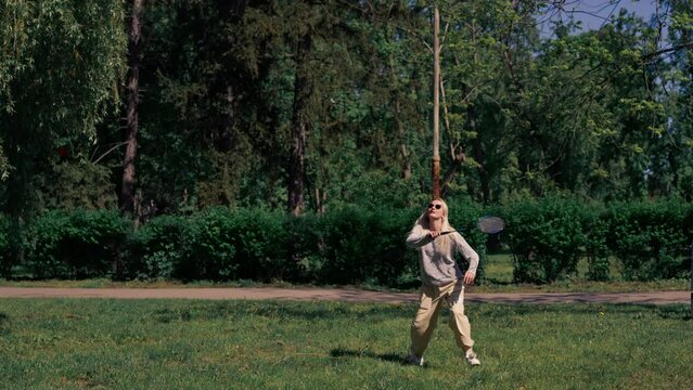 outdoors in a park with trees a young brunette guy with a blonde girl playing bambinton best friends relaxing together the girl serves