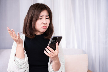 upset Asian woman made a mistake losing money to scam calls  holding smart phone with serious face